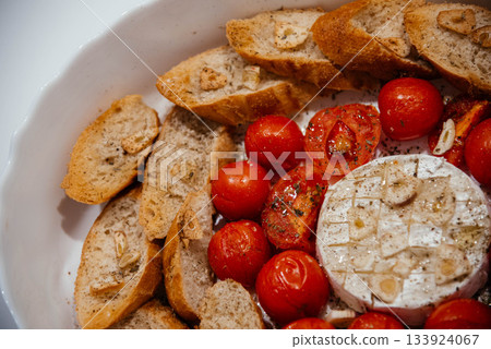 Camembert cheese baked with tomatoes and baguette, herbs and garlic. An excellent appetizer for wine. View from above. Camembert cheese baked with tomatoes and baguette, herbs and garlic. An excellent appetizer for wine. View from above. 133924067