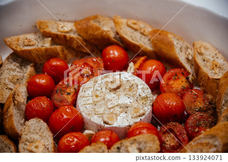 Camembert cheese baked with tomatoes and baguette, herbs and garlic. An excellent appetizer for wine. View from above. Camembert cheese baked with tomatoes and baguette, herbs and garlic. An excellent appetizer for wine. View from above. 133924071