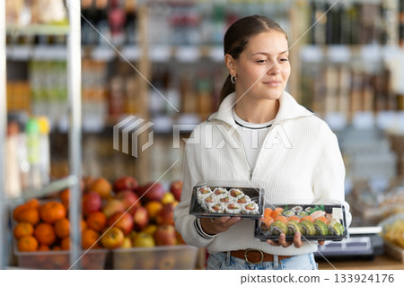 Young woman choosing packaged sushi and rolls 133924176