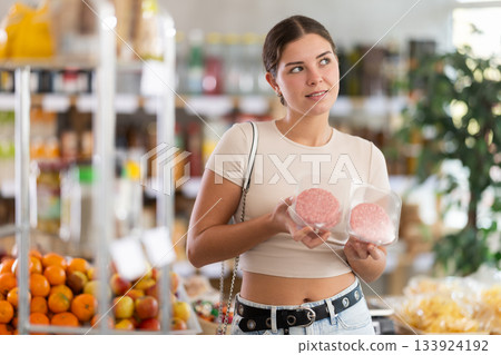 Young woman choosing hamburger in grocery store Young woman choosing hamburger in grocery store 133924192