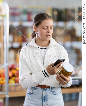 Woman scanning a jar of olives on her phone Woman scanning a jar of olives on her phone 133924242