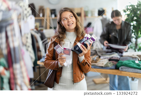 Positive young girl choosing socks in clothing store Positive young girl choosing socks in clothing store 133924272