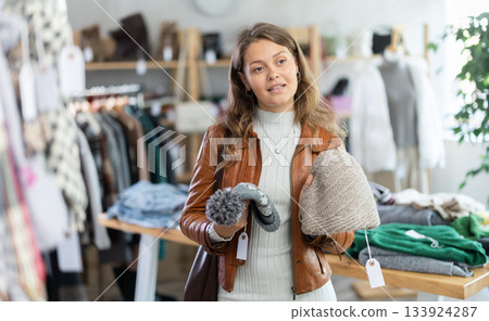 Young woman choosing hat in clothing store Young woman choosing hat in clothing store 133924287