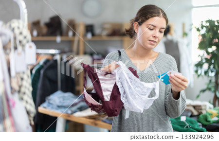 Uncertain young girl choosing panties in clothing store 133924296