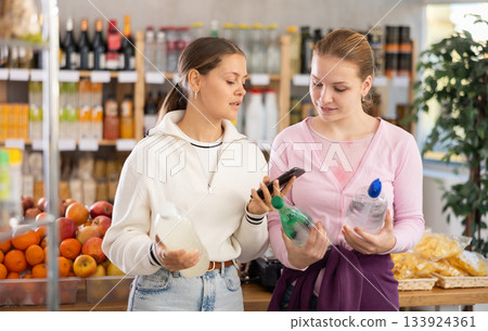 Two customers scanning the barcode of soda bottles 133924361