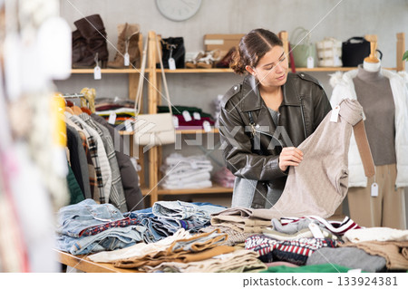 Selective young girl choosing trousers in clothing store Selective young girl choosing trousers in clothing store 133924381