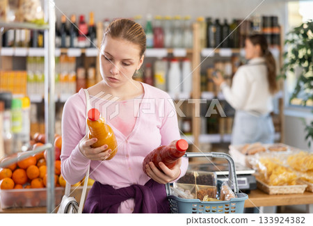 woman chooses juices against the background of buyers woman chooses juices against the background of buyers 133924382