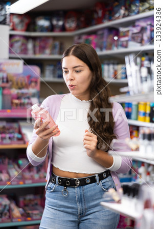 Young woman customer choosing shower gel at supermarket 133924386
