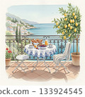 Scenic seaside balcony breakfast overlooking a Mediterranean view. A round table with a floral tablecloth holds croissants, berries, and juice 133924545