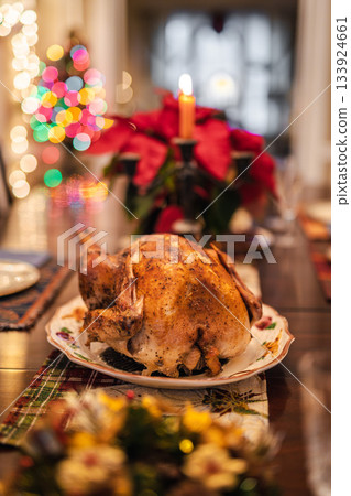 Christmas roasted turkey served on a festive holiday table with candles, poinsettias, and colorful Christmas lights creating a warm seasonal atmosphere. 133924661