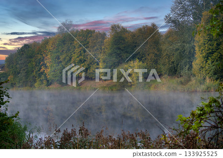 Mist Over Quiet Lake At Dawn Surrounded By Autumn Trees And Calm Forest Mist Over Quiet Lake At Dawn Surrounded By Autumn Trees And Calm Forest 133925525