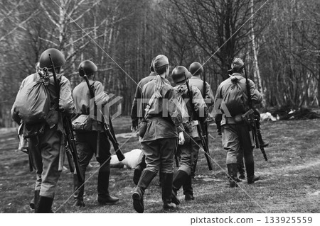 Group Of Re-enactors Dressed As Soviet Russian Soldiers Escort Civilians. Soviet Russian Soldiers Uniform. Evacuation Of Civilians. Black And White Video Group Of Re-enactors Dressed As Soviet Russian Soldiers Escort Civilians. Soviet Russian Soldiers Uniform. Evacuation Of Civilians. Black And White Video 133925559