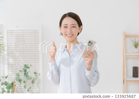 一位四十多歲的女性拿著智慧型手機 133925687