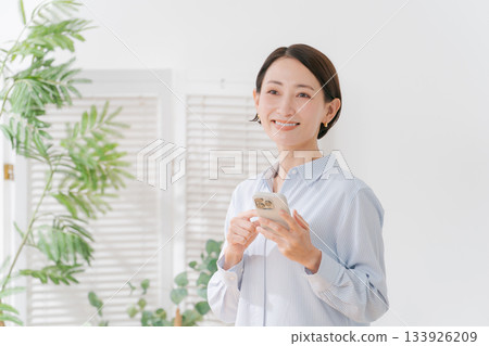 A woman in her 40s holding a smartphone A woman in her 40s holding a smartphone 133926209