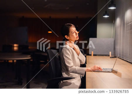 一位女經理在辦公室加班到天黑，已經筋疲力盡。 133926785