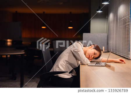 一位女經理在辦公室加班到天黑，已經筋疲力盡。 133926789