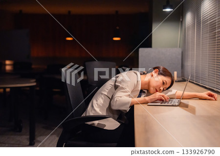 一位女經理在辦公室加班到天黑,已經筋疲力盡。 一位女經理在辦公室加班到天黑,已經筋疲力盡。 133926790