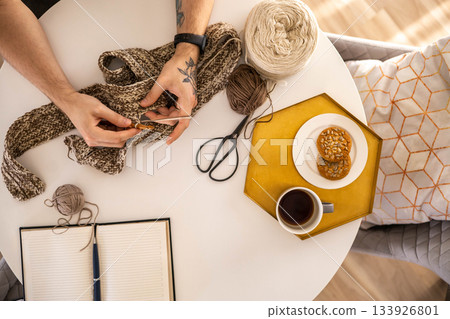 Feminine male hands crochet handmade artwork hobby wooden table with sewing tools closeup top view Feminine male hands crochet handmade artwork hobby wooden table with sewing tools closeup top view 133926801