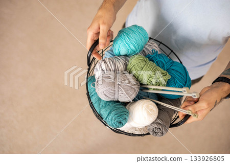 A man holds a large basket with colorful yarn. A man holds a large basket with colorful yarn. 133926805