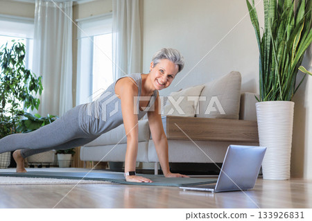 Smiling mature elderly gray-haired beautiful athletic woman doing yoga, pilates 133926831