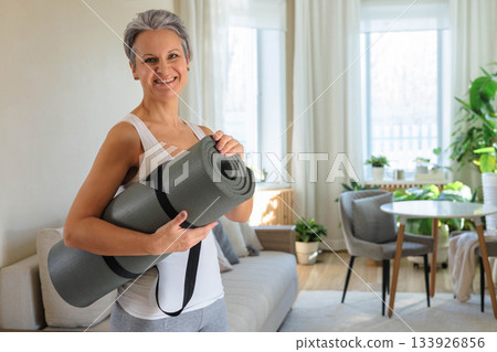 Smiling mature gray haired sport woman with yoga roll mat posing isolated. Happy mid age senior Smiling mature gray haired sport woman with yoga roll mat posing isolated. Happy mid age senior 133926856