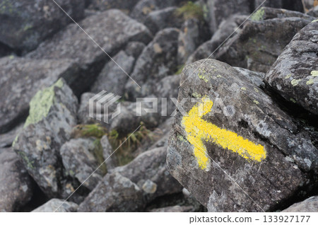 Yellow arrow painted on the rock: A signpost indicating the hiking trail 133927177