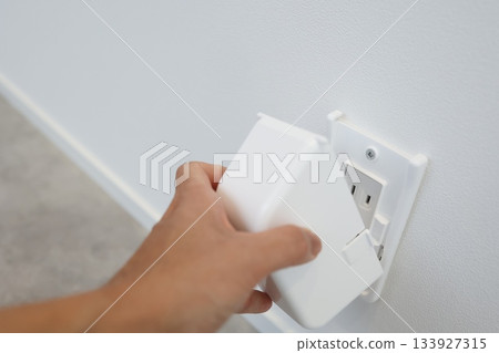 A scene showing the installation of an outlet cover to prevent electric shock and tampering. A concept of safety measures. 133927315