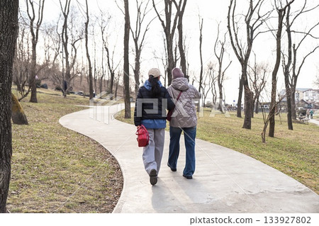 Two Russian friends walking in Nagaorny Park in Vladivostok, enjoying mindful movement and calm conversation that supports wellbeing, freedom and positive connection. Two Russian friends walking in Nagaorny Park in Vladivostok, enjoying mindful movement and calm conversation that supports wellbeing, freedom and positive connection. 133927802