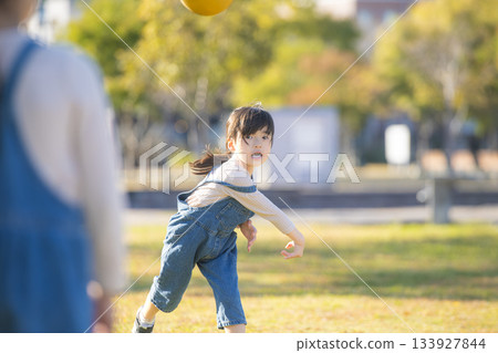A cheerful girl playing with a ball in the park A cheerful girl playing with a ball in the park 133927844