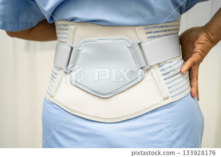 Asian senior pain back wearing elastic support belt with walker. 133928176