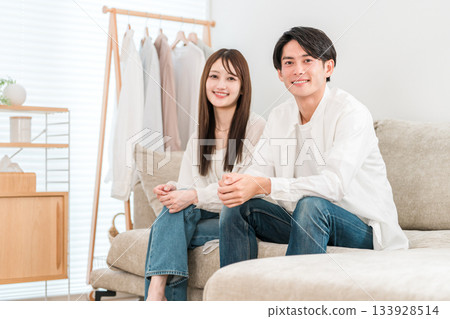 一對年輕的亞洲夫婦坐在家裡客廳的沙發上 一對年輕的亞洲夫婦坐在家裡客廳的沙發上 133928514