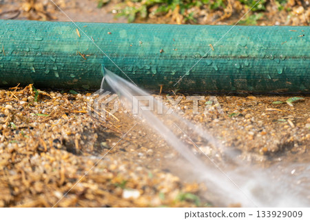 Water leaking from hole in a industrial hose. Water leaking from hole in a industrial hose. 133929009