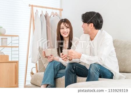 Young couple relaxing on the sofa with a hot drink Young couple relaxing on the sofa with a hot drink 133929319