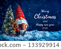 Long white beard gnome with red pattern hat holding red coffee mug standing next to illuminated Christmas tree on snowy ground in snowing night 133929914