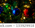 Closeup of Christmas tree with deep blue and deep red ornaments hanging. 133929918