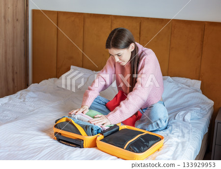 Woman packing suitcase on bed for travel vacation Woman packing suitcase on bed for travel vacation 133929953