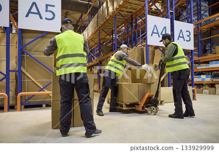 Warehouse workers loading boxes onto pallet jack for efficient order dispatch Warehouse workers loading boxes onto pallet jack for efficient order dispatch 133929999