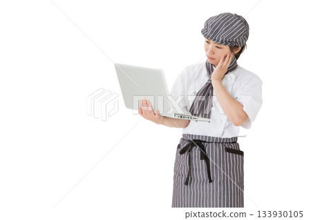 A woman wearing a chef's coat using a laptop 133930105