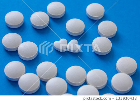 Heart shaped and round white pills on blue background. Global healthcare concept. Health and Medicine. Love concept for Valentine's day with love pills. Heart shaped and round white pills on blue background. Global healthcare concept. Health and Medicine. Love concept for Valentine's day with love pills. 133930438