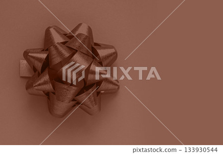 Christmas composition with Bow of the color Mocha Mousse with copy space. Demonstrating the colors of 2025. 133930544