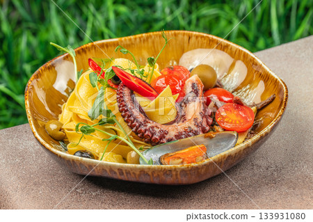 Mediterranean seafood pasta with octopus, mussels, cherry tomatoes and olives served in a rustic bowl for gourmet menu design and food advertising Mediterranean seafood pasta with octopus, mussels, cherry tomatoes and olives served in a rustic bowl for gourmet menu design and food advertising 133931080