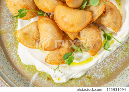 Crispy fried dumplings served on creamy sour cream with microgreens and olive oil on a rustic plate 133931094