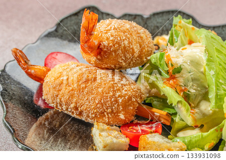 Crispy breaded shrimp skewers served with fresh salad and vegetables on a restaurant plate for gourmet seafood concept Crispy breaded shrimp skewers served with fresh salad and vegetables on a restaurant plate for gourmet seafood concept 133931098