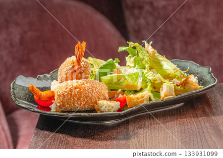 Crispy breaded shrimp skewers served with fresh salad and vegetables on a restaurant plate for gourmet seafood concept Crispy breaded shrimp skewers served with fresh salad and vegetables on a restaurant plate for gourmet seafood concept 133931099