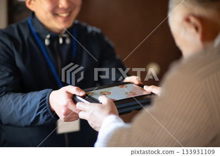 An elderly man receiving a home-delivered lunch box 133931109