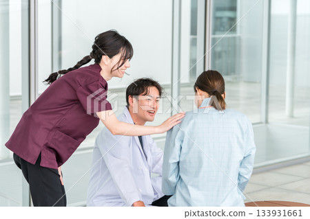 一名護士和一名男醫生在醫院的屋頂露臺上與一名女病人交談。 133931661