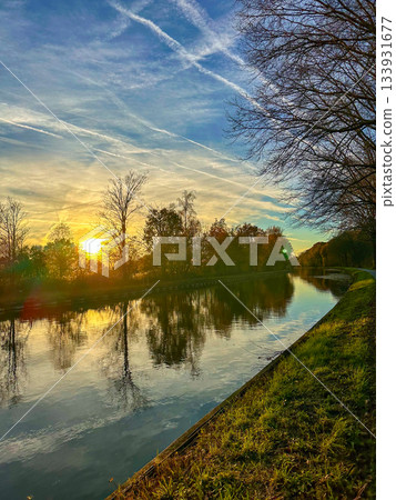 Calm water captures vibrant amber hues and peaceful surroundings Calm water captures vibrant amber hues and peaceful surroundings 133931677