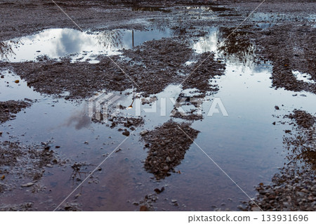 Mud Puddles Reflecting Sky and Trees on a Wet Outdoor Path After Rain Mud Puddles Reflecting Sky and Trees on a Wet Outdoor Path After Rain 133931696