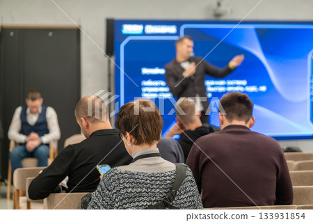 Business seminar audience listening to a speaker on stage during a modern corporate presentation Business seminar audience listening to a speaker on stage during a modern corporate presentation 133931854