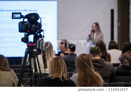 Conference presentation with camera filming audience and speaker in bright modern seminar room Conference presentation with camera filming audience and speaker in bright modern seminar room 133931857